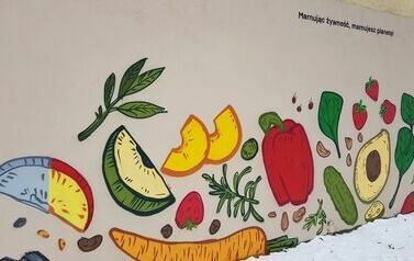 Owoce i warzywa namalowane sprayem na murze. Napis: Marnując żywność, marnujesz planetę.