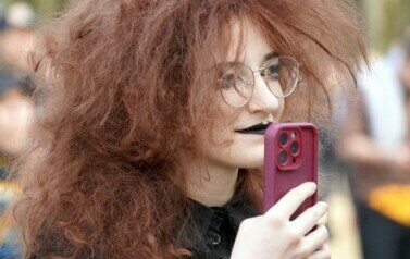 Uczestniczka koncertu trzymająca telefon w ręku