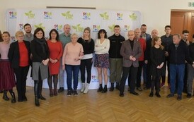 grupa ludzi na tle baneru w białe i zielone logotypy