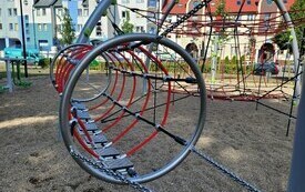 Plac zabaw, urządzenie zabawowe. W tle zabudowa wielorodzinna.