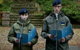 Zdjęcie przedstawia dwoje uczni&oacute;w klas wojskowych w mundurach przemawiających do mikrofon&oacute;w.
