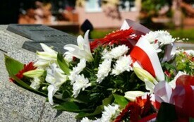 Biało-czerwone kwiaty leżące na pomniku.
