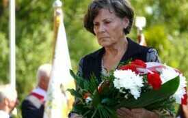Kobieta niosąca wieniec biało-czerwonych kwiat&oacute;w.
