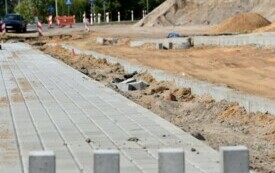 Plac budowy drogi, chodnik wyłożony kostką brukową na pierwszym planie