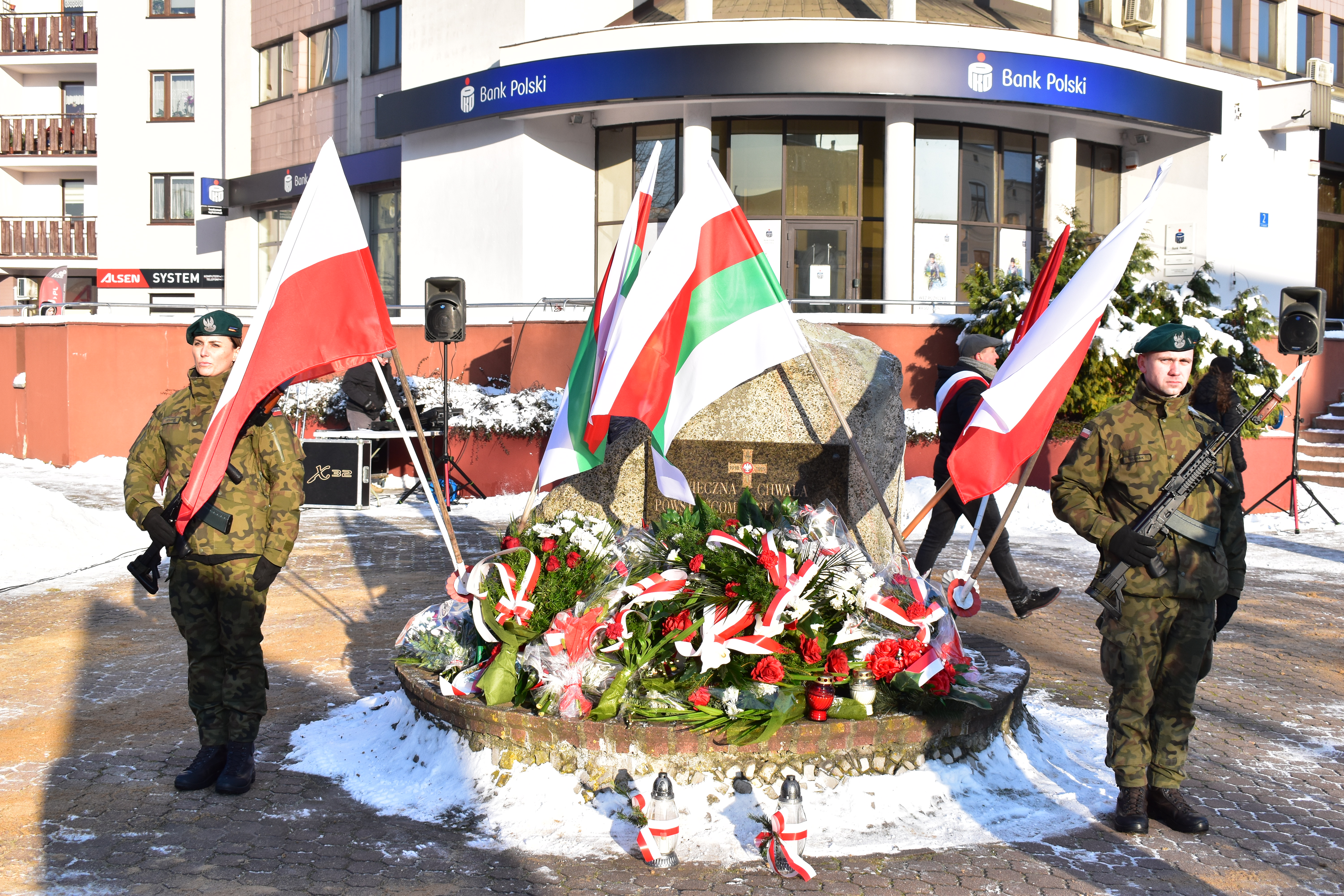 warta przed pomnikiem, pod pomnikiem kwiaty i znicze