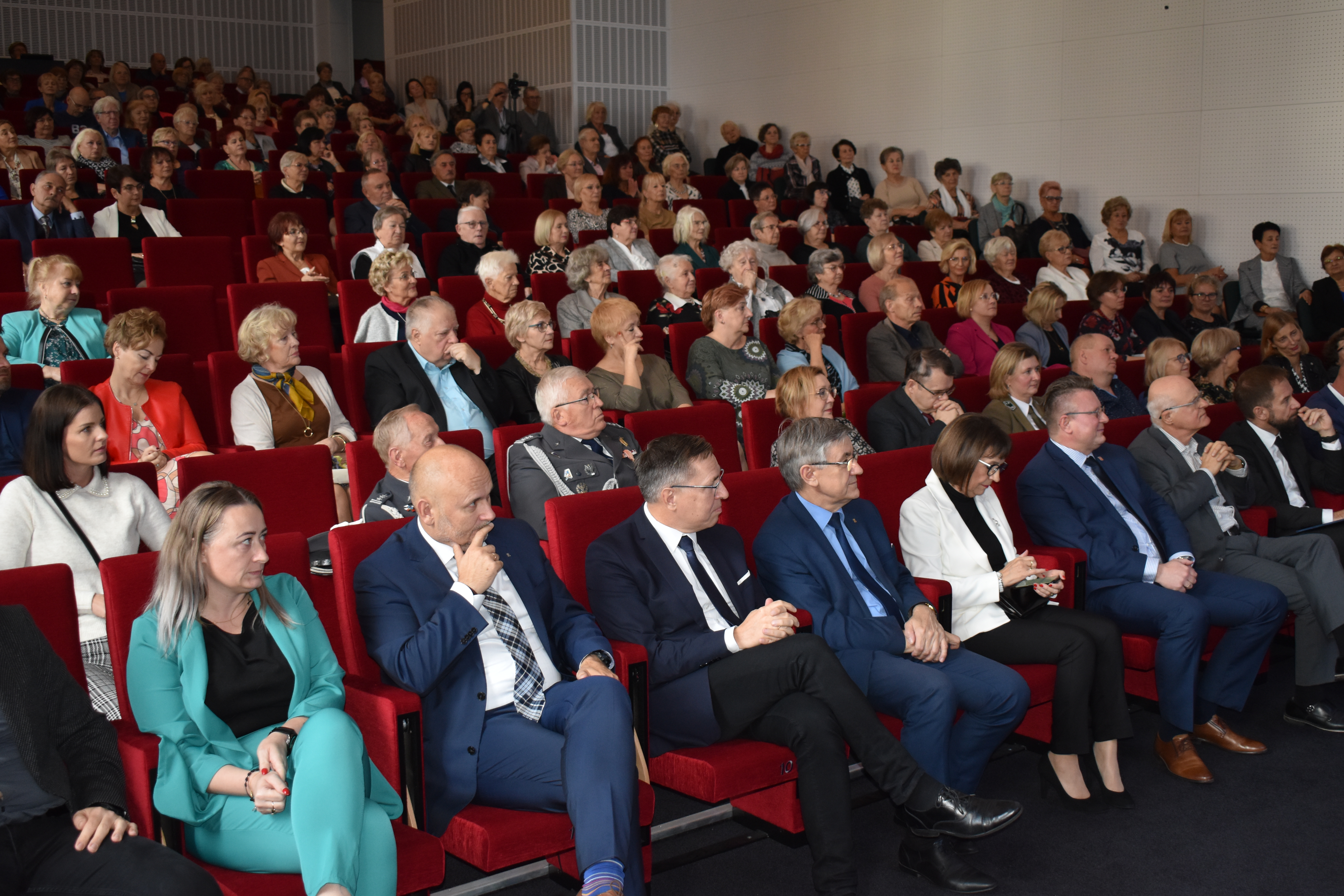 Sala widowiskowa. Kobiety i mężczyźni siedzą w fotelach.