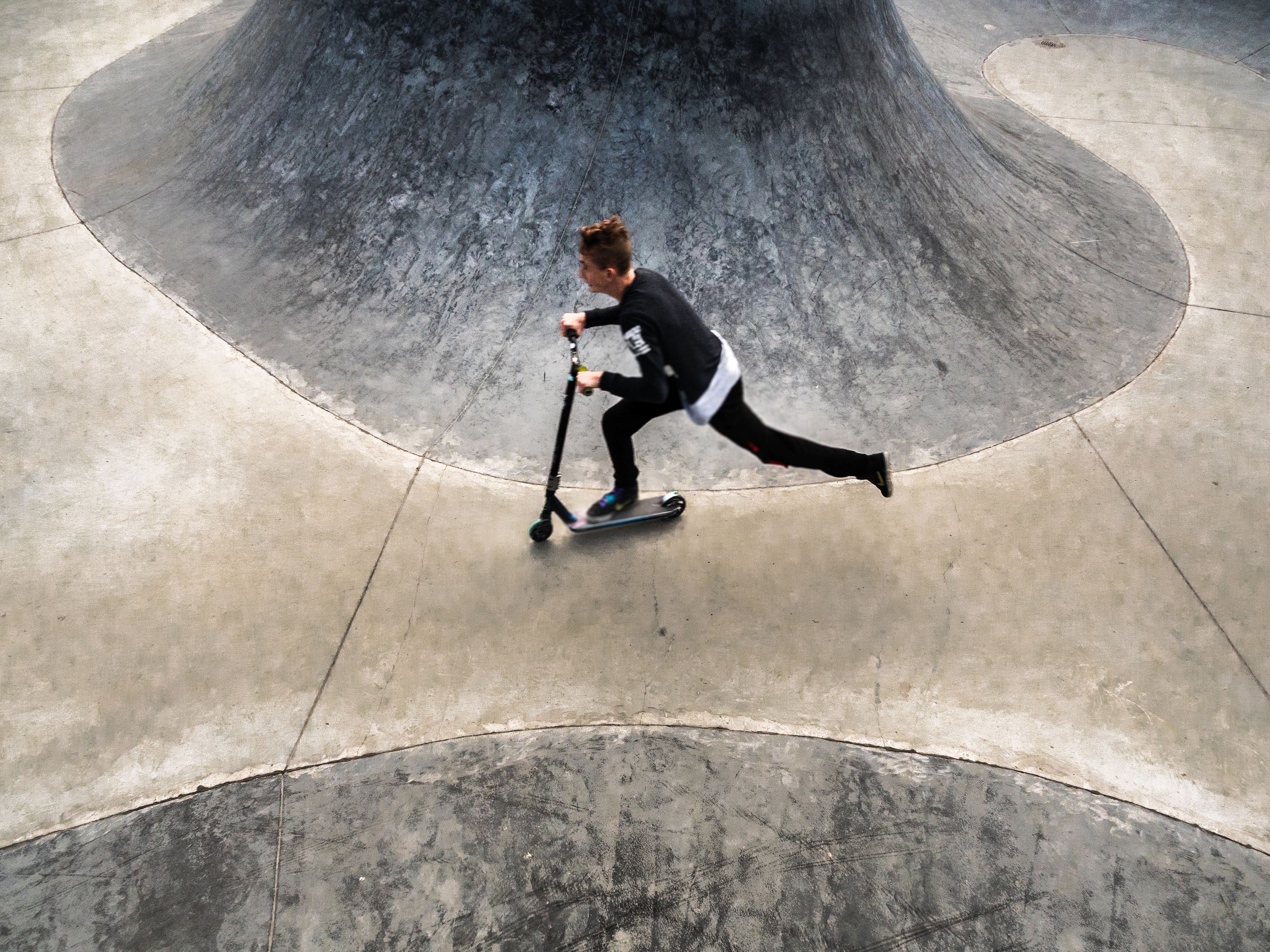 Chłopiec jedzie na&nbsp;hulajnodze. Elementy skateplazy. 