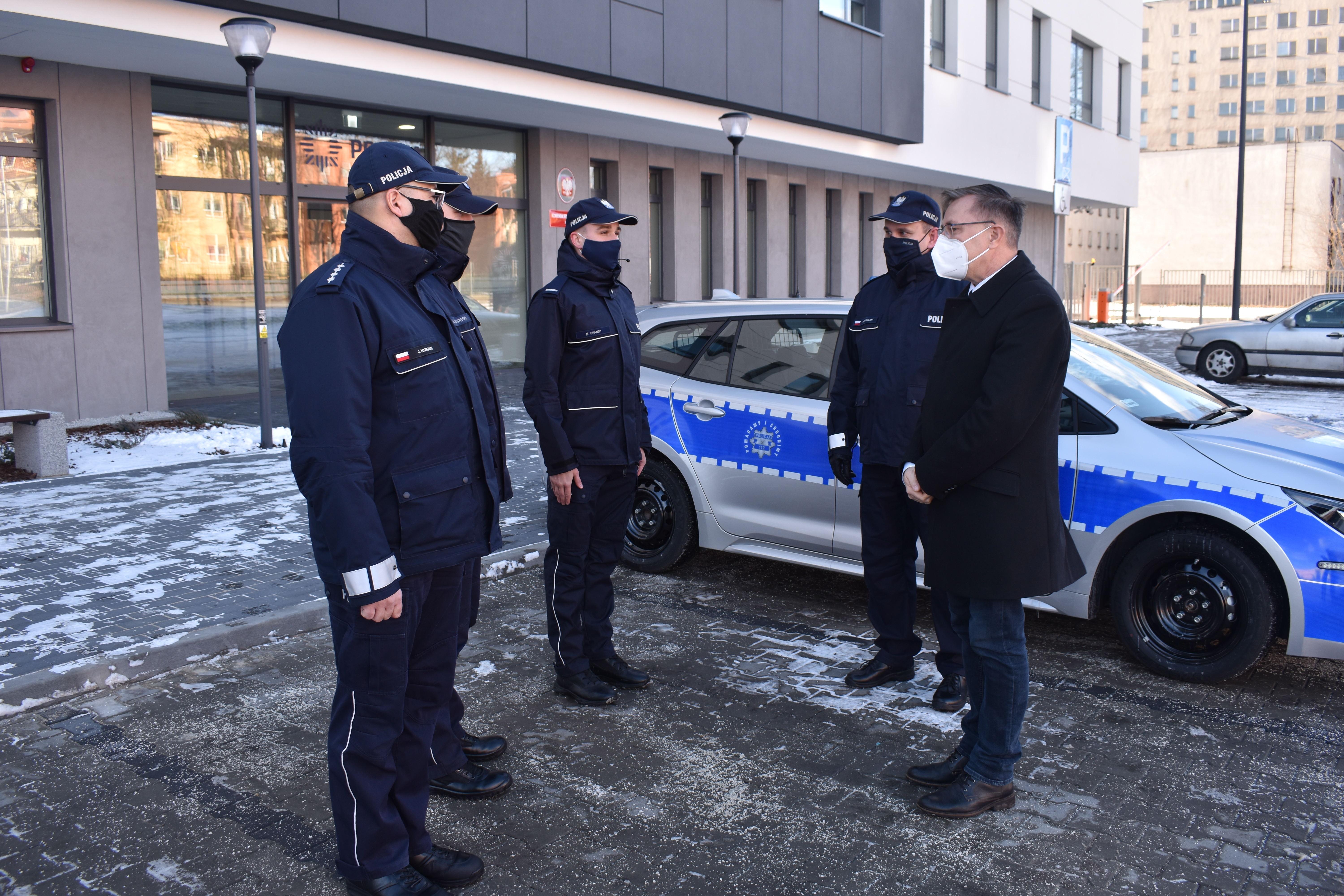 Czterech policjantów i mężczyzna. Radiowóz policji.