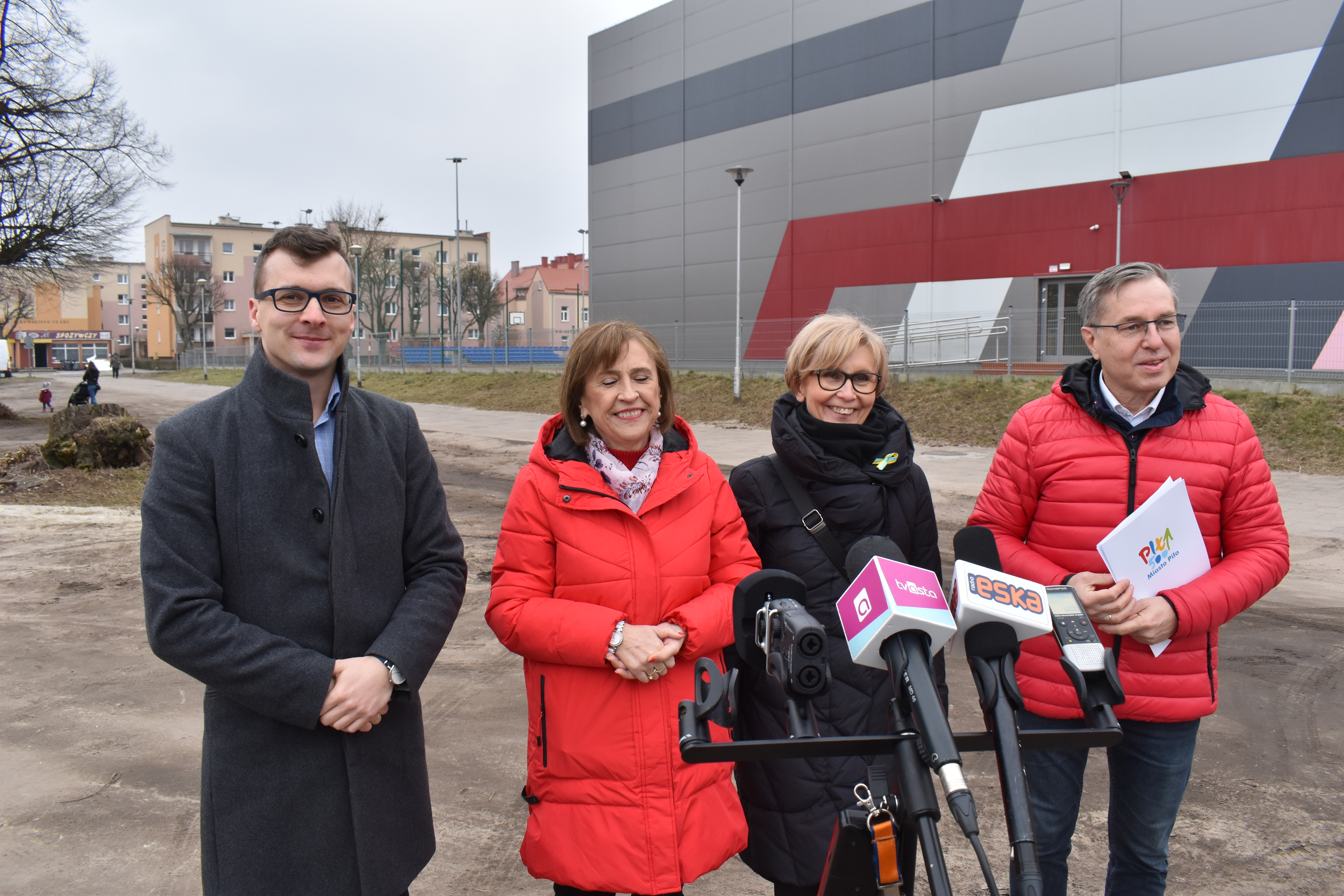 Miasto. Duży budynek. Dwie kobiety i&nbsp;dwaj mężczyźni stoją.