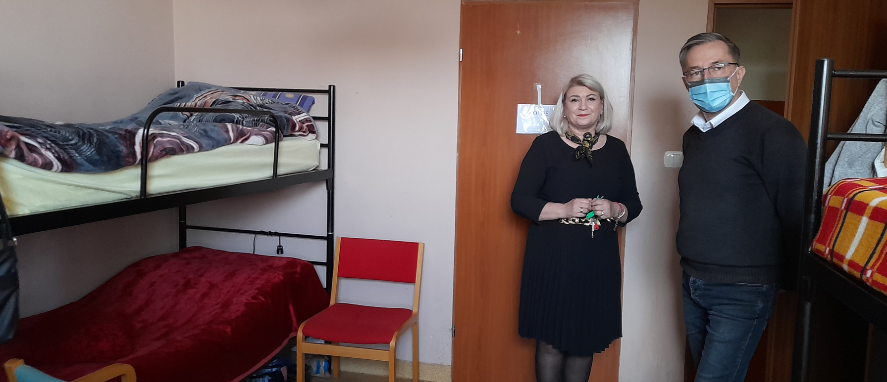 Kobieta i mężczyzna stoją w pokoju mieszkalnym. Piętrowe łózka.