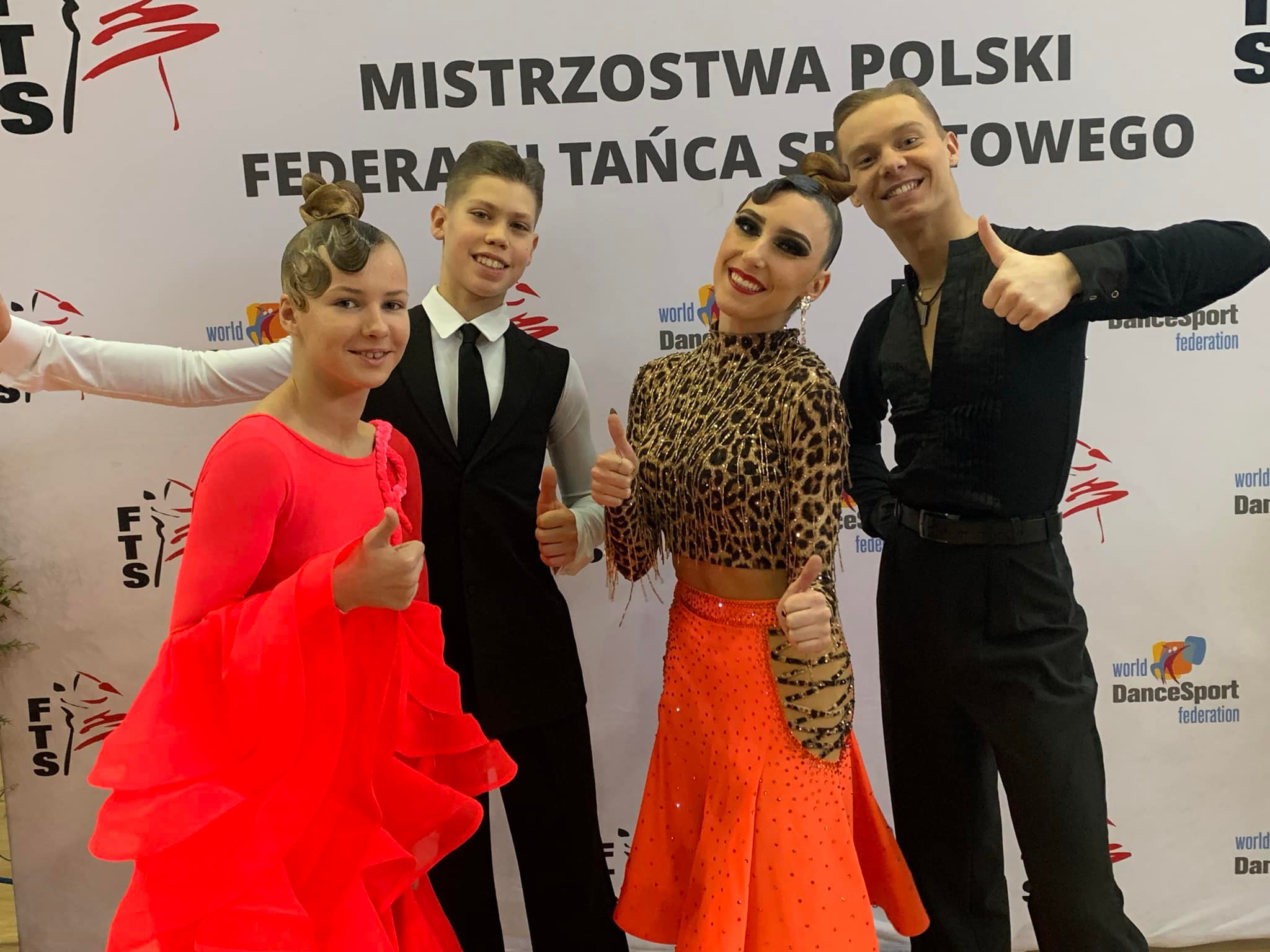 Wsparcie kolejnych klubów sportowych Dwie pary tancerzy tańca towarzyskiego pozuje przy ściance, na której jest napis: Mistrzostwa Polski w Tańcu Sportowym