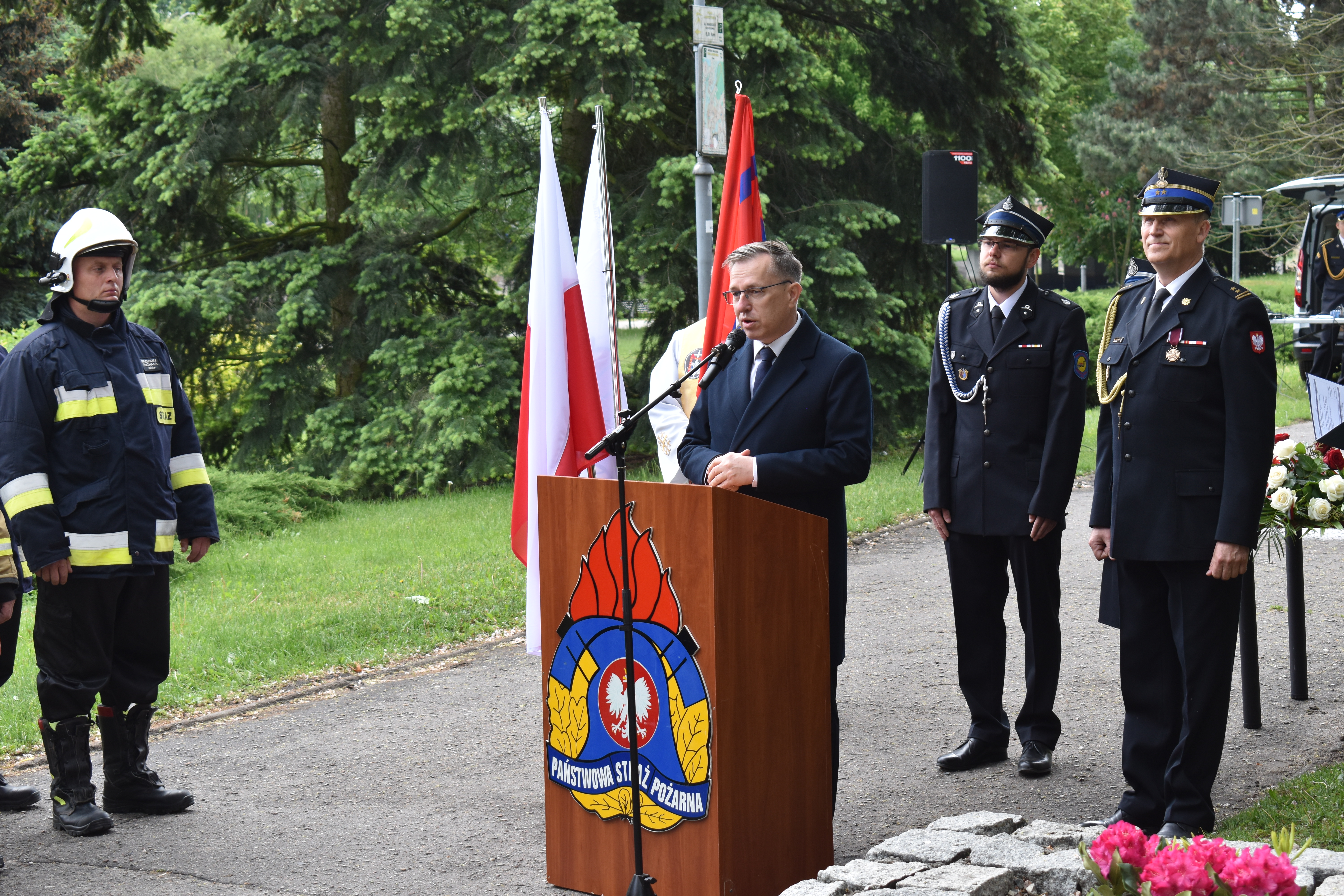 Mężczyna stoi przy mównicy. Starż pożarna.