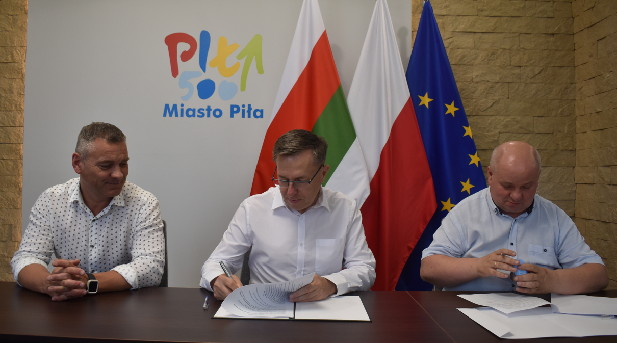 reprezentacyjne pomiszczenie. Trzech mężczyn podpisuje dokumenty.