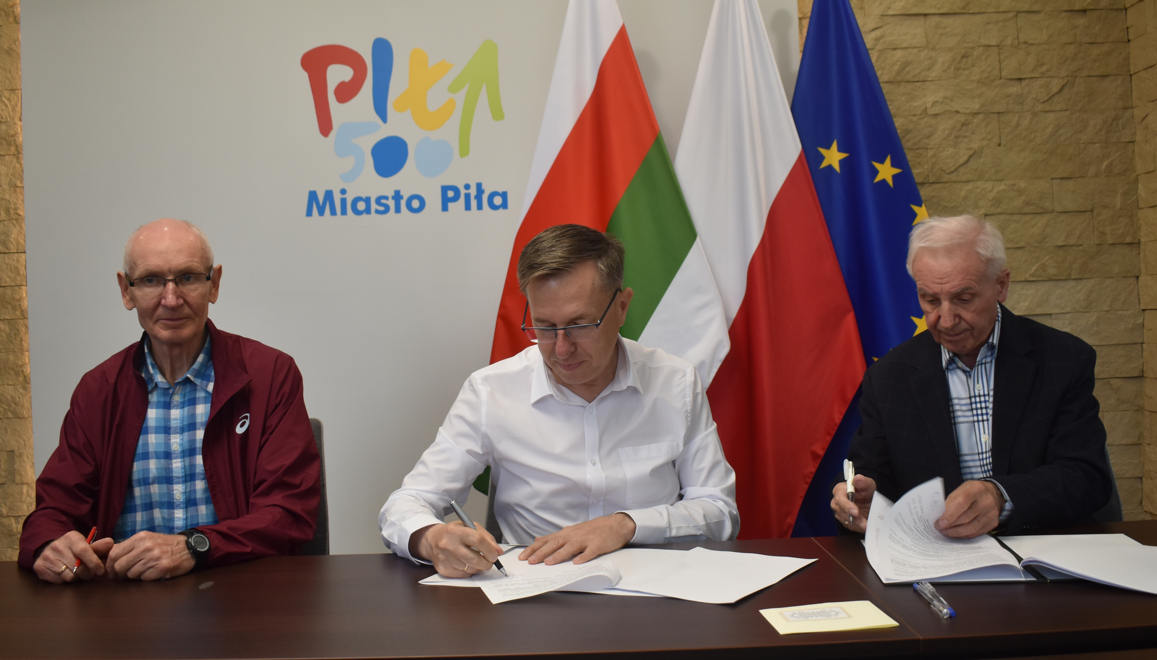 reprezentacyjne pomiszczenie. Trzech mężczyn podpisuje dokumenty.