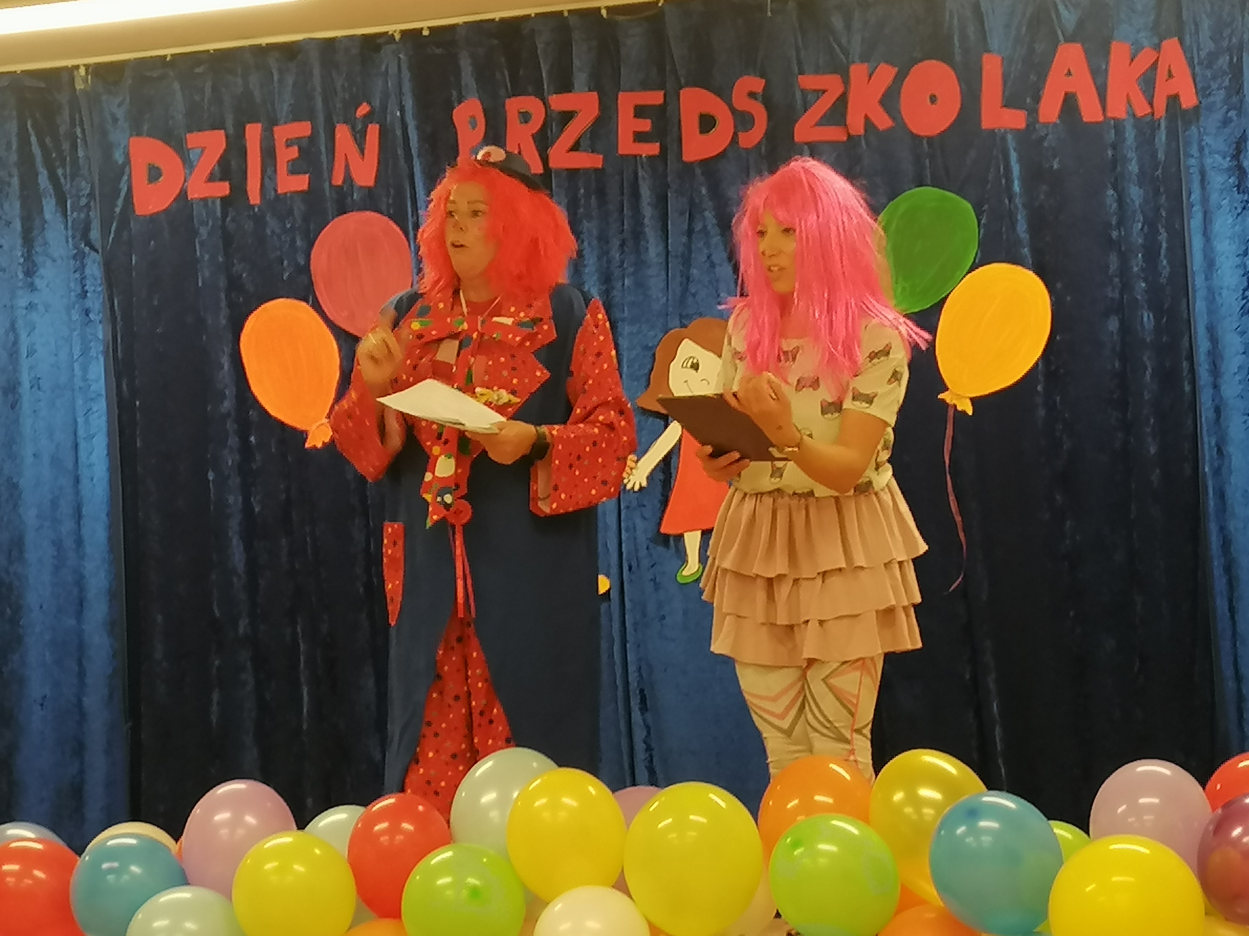 Ogólnopolski Dzień Przedszkolaka Dwóch klaunów na scenie. W tle napis Dzień Przedszkolaka. Z przodu kilkadziesiąt kolorowych, nadmuchachnych powietrzem balonów.
