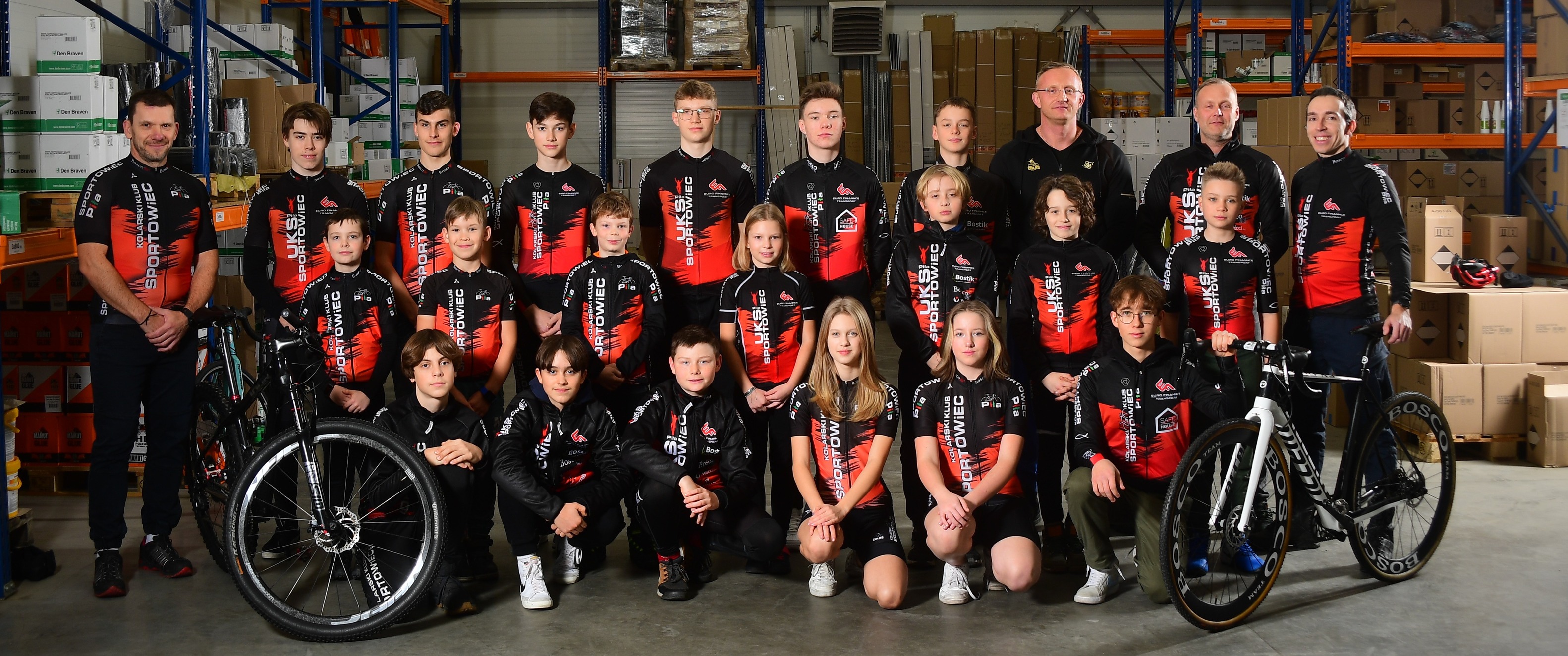 10 000 złotych na szkolenie w kolarstwie Grupa kilkunastu osób - młodych zawodników i trenerów w jednakowych strojach z napisem Kolarski Klub Sportowiec, obok nich dwa rowery.