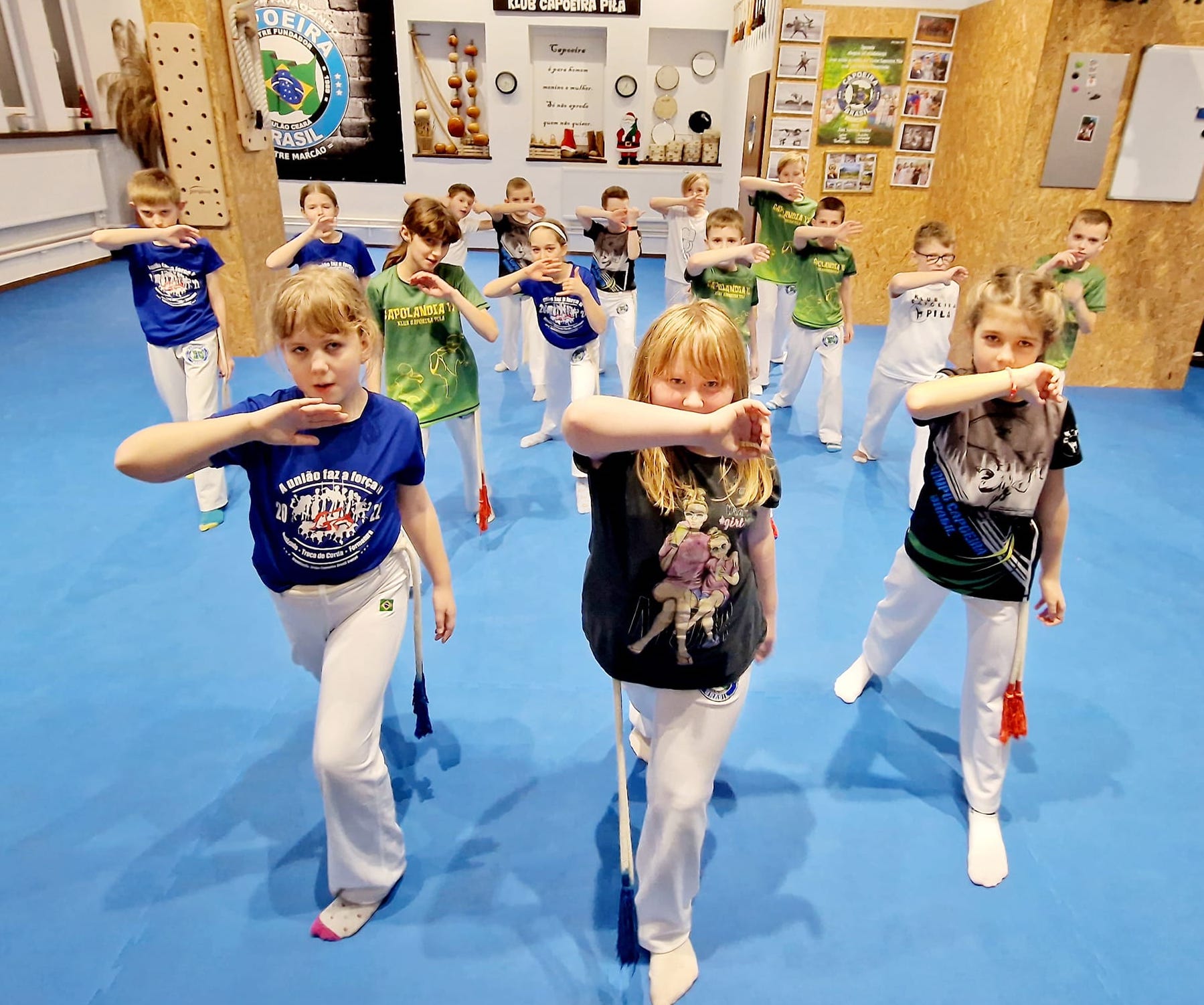 11 500 złotych na szkolenie Capoeira! Grupa dzieci ćwiczących na sali sportowej, w tle na ścianie napis: Klub Capoeira Piła.