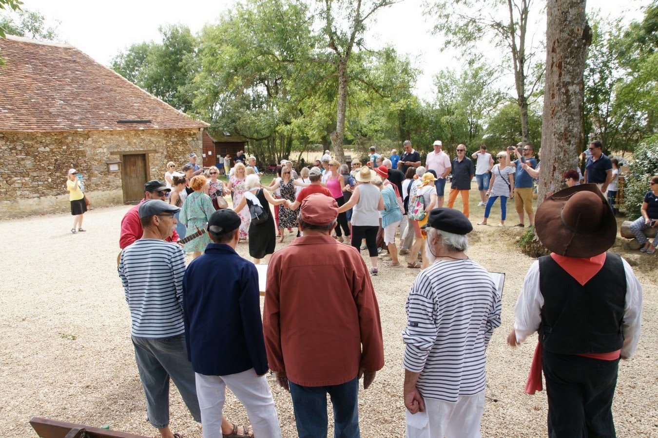 Wizyta pilan w partnerskim mieście Châtellerault, 2019 rok Grupa ludzi na świeżym powietrzu w ciepły dzień, w tle ceglany budynek. Część ludzi trzyma się za ręce, tańczy.