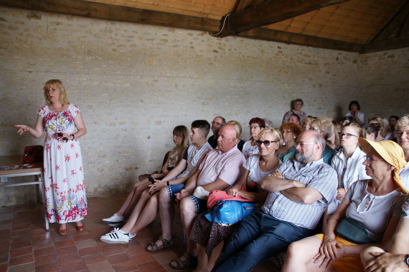 Wizyta pilan w partnerskim mieście Châtellerault, 2019 rok Grupa ludzi w pomieszczeniu, część siedzi na krzesłach, jedna z kobiet stoi przed grupą i opowiada coś reszcie.