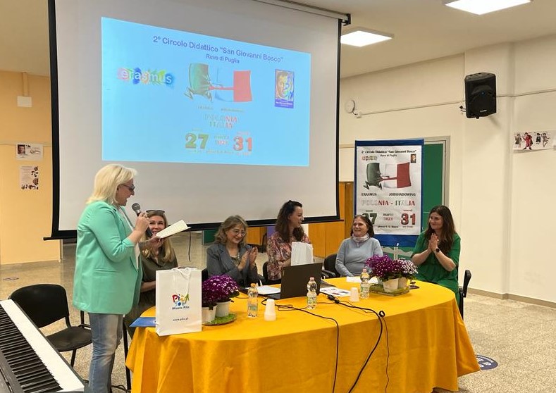 szkoleniu zorganizowanym w ramach projektu szkolenia kadry pedagogicznej Erasmus+ KA1 , tytuł projektu: „Samodzielnie Tworzę, Eksperymentuję, Myślę - akademia kompetencji przyszłości.” W pomieszczenie przy stole siedzi pięć kobiet, które słuchają co mówi szósta kobieta. Na stole stoi laptop i kwiaty. W tle na ekranie wyświetlania jest multimedialna prezentacja.