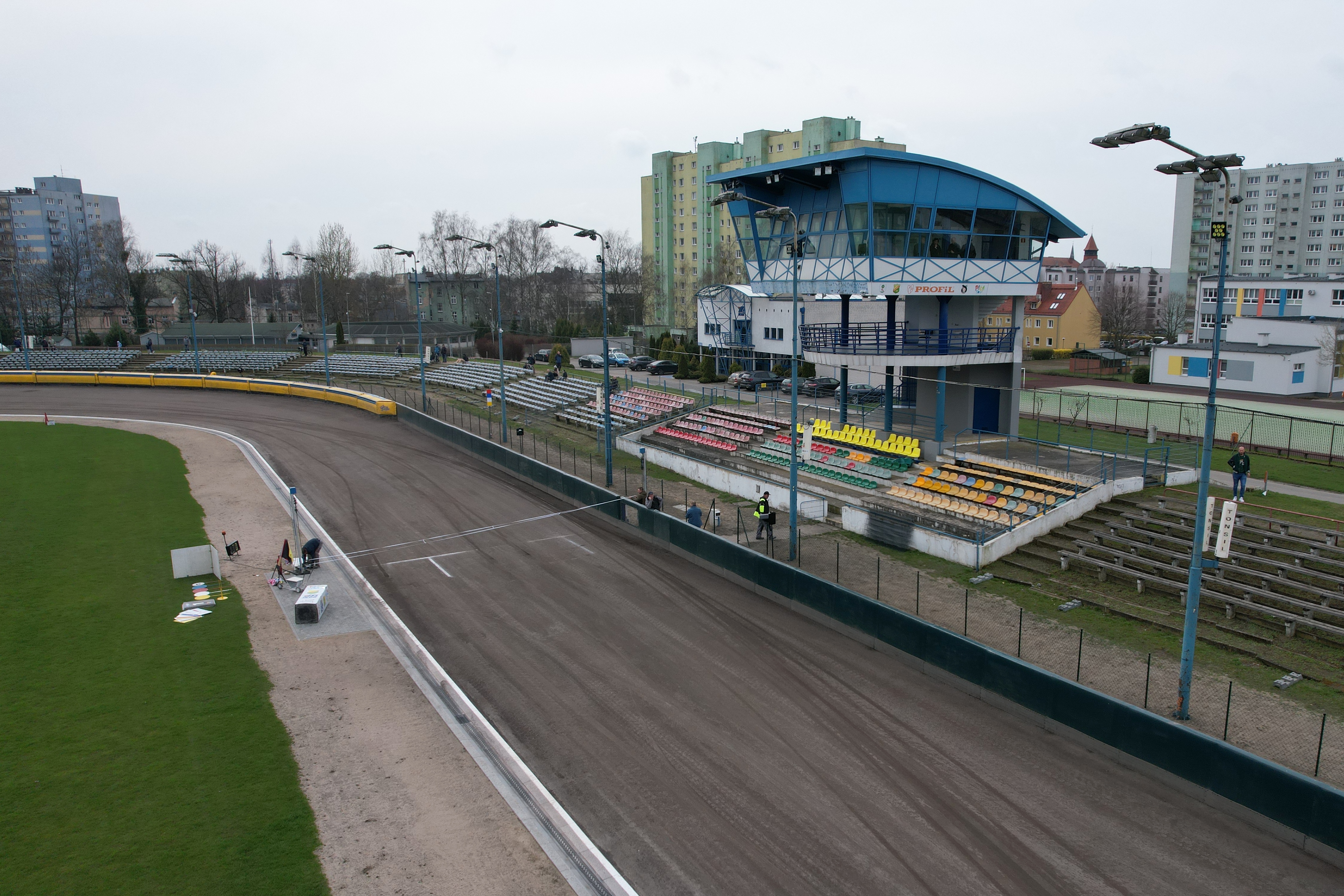 Fragment stadionu żużlowego. Na pierwszym planie start i meta, tor, trybuny i wieża stadionowa.