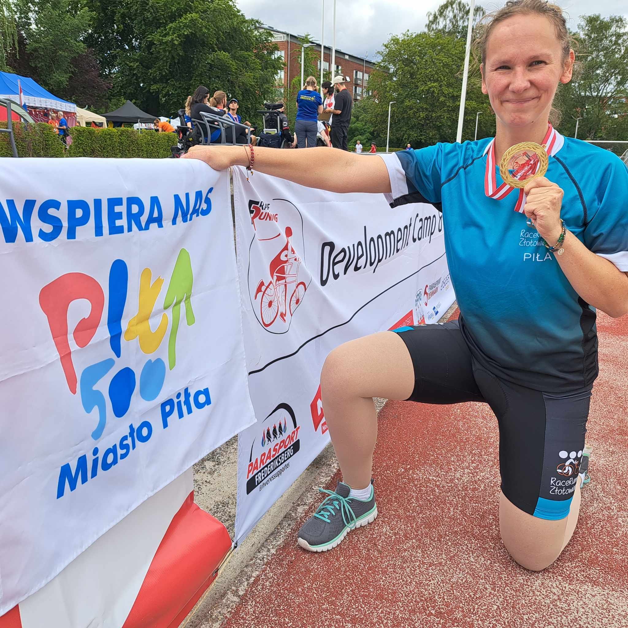 Magdalena Andruszkiewicz, potrójne złoto na zawodach w Kopenhadze Kobieta w sportowym stroju, trzyma w ręce zawieszony na szyi złoty medal. Po lewej stronie na barierce zawieszona flaga z napisem Wspiera nas Miasto Piła
