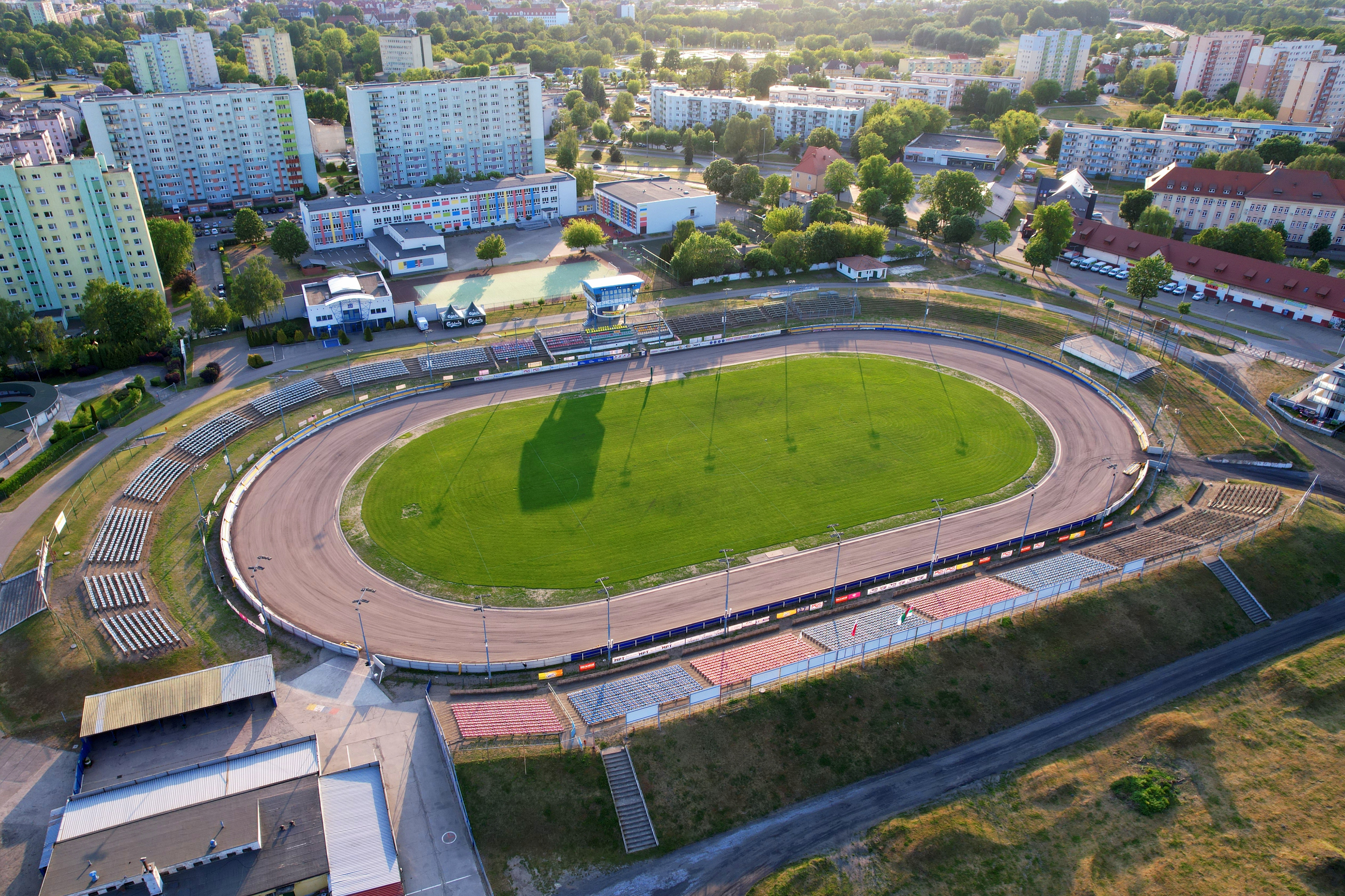 Stadion przy Bydgoskiej i inne inwestycje realizowane w Pile Stadion z lotu ptaka. Trawiasta płyta boiska, żużlowa bieznia, puste trybuny, wieża stadionowa. Dookoła stadionu wielorodzinne budynki mieszkalne.