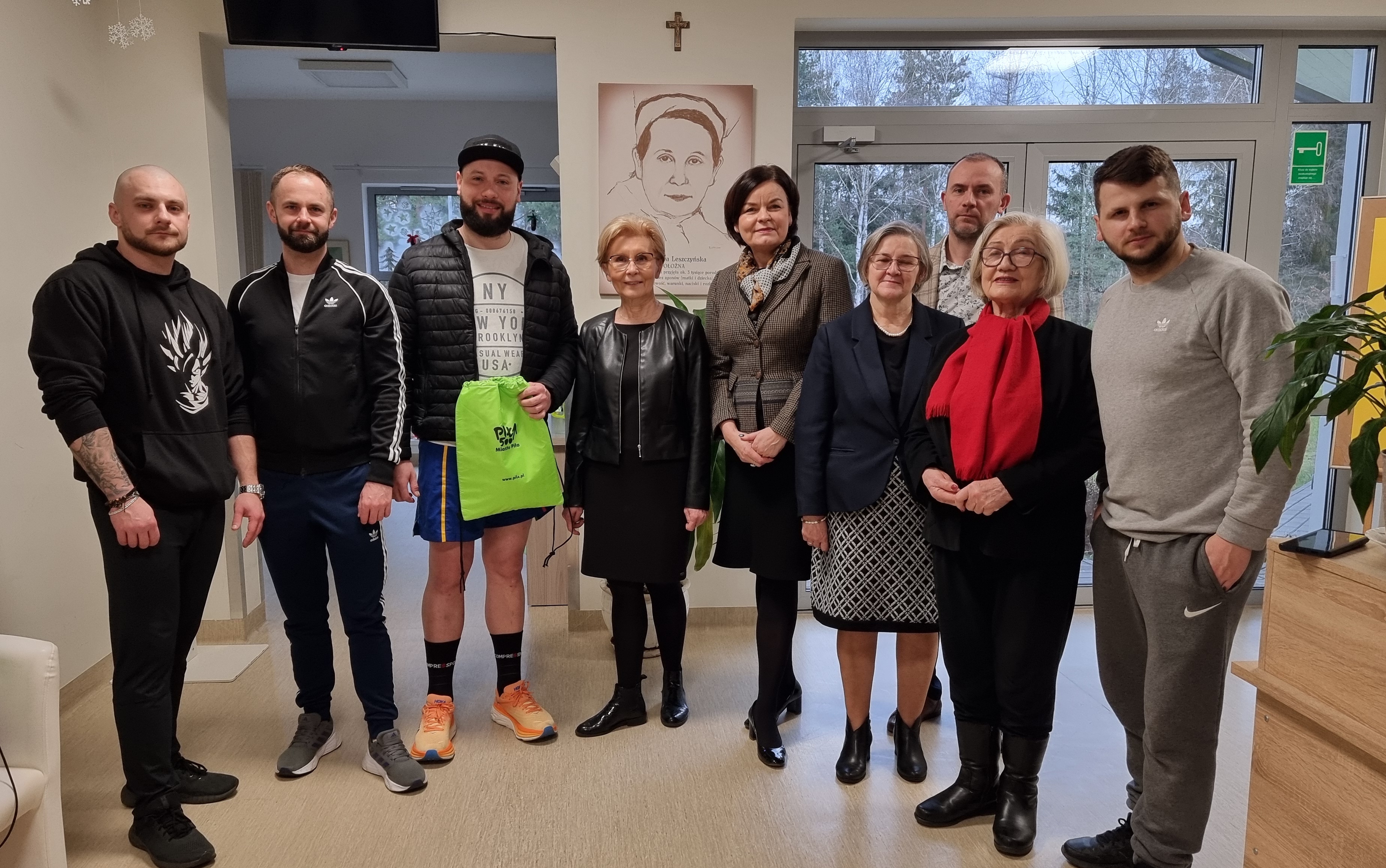 Grupowe zdjęcie, na&nbsp;kt&oacute;rym znajduje się pięciu mężczyzn oraz&nbsp;cztery kobiety. Stoją w&nbsp;środku budynku.
