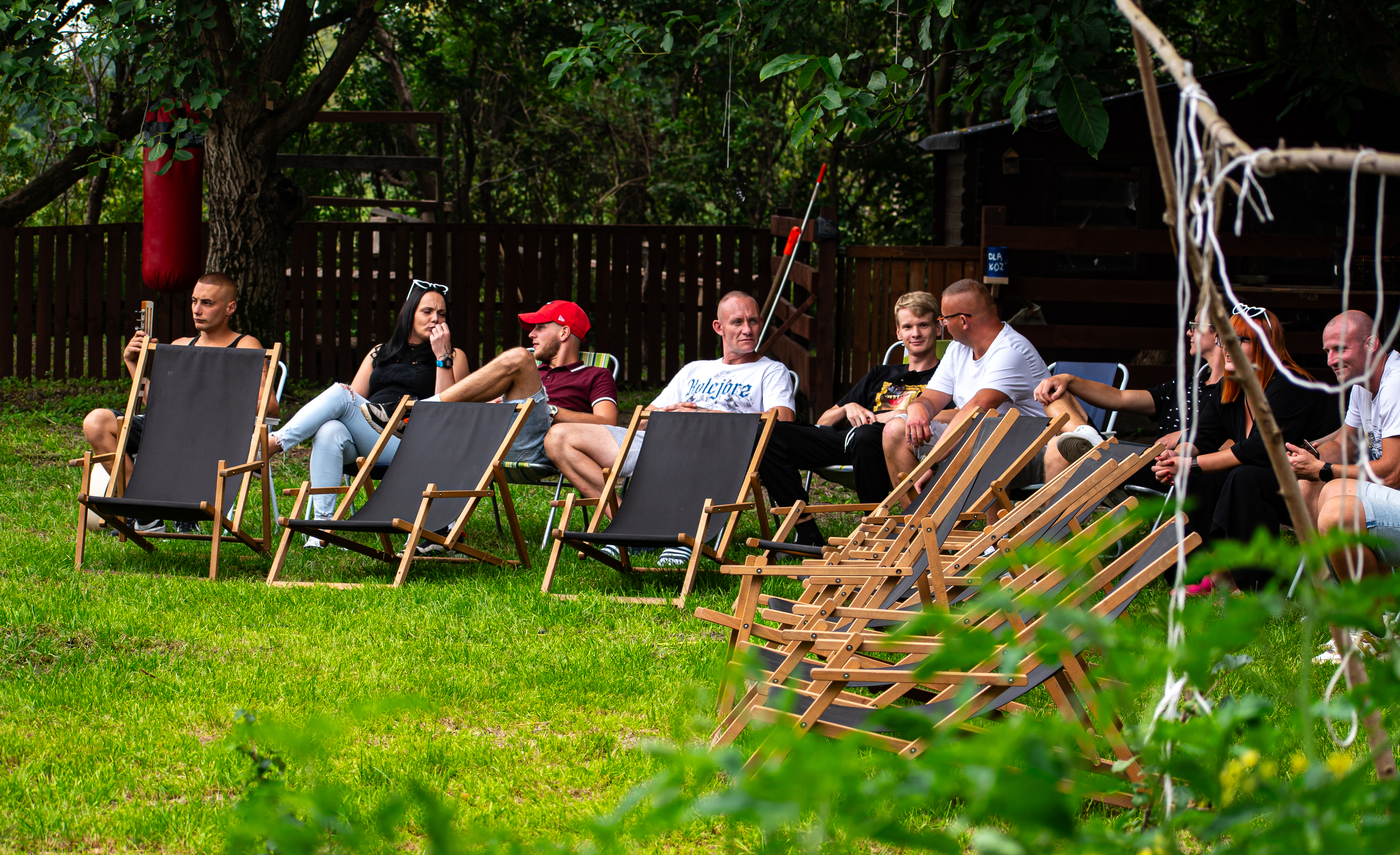 Kilka os&oacute;b siedzących na&nbsp;leżakach na&nbsp;dworze.
