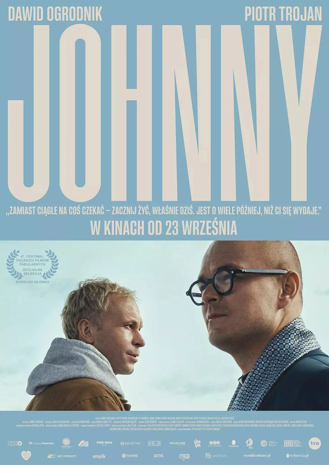 Niebieskie tło, na zdjęciu dwóch mężczyzn. Treść: Dawid Ogrodnik, Piotr Trojan Johnny "Zamiast ciągle na coś czekać - zacznij żyć, właśnie dziś. Jest o wiele później niż ci się wydaje".