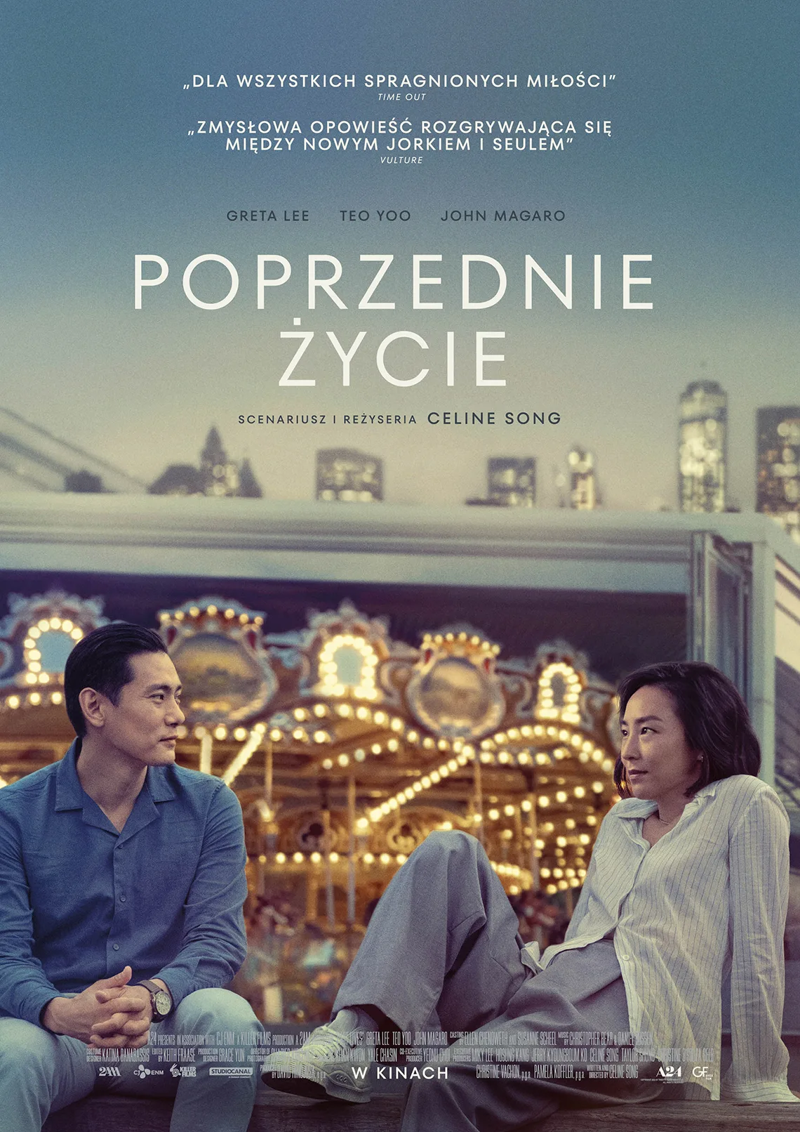 Kobieta i mężczyzna siedzą na murku, w tle za nimi podświetlona karuzela, wysokie budynki. Treść: poprzednie życie, scenariusz i reżyseria: Celine Song