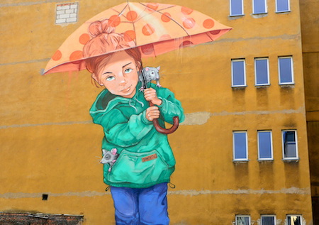 Mural na ścianie budynku przedstawiający dziewczynkę, która trzyma nad głową parasolkę. Z kieszeni wystaje jeden szczur, na ramieniu siedzi drugi.